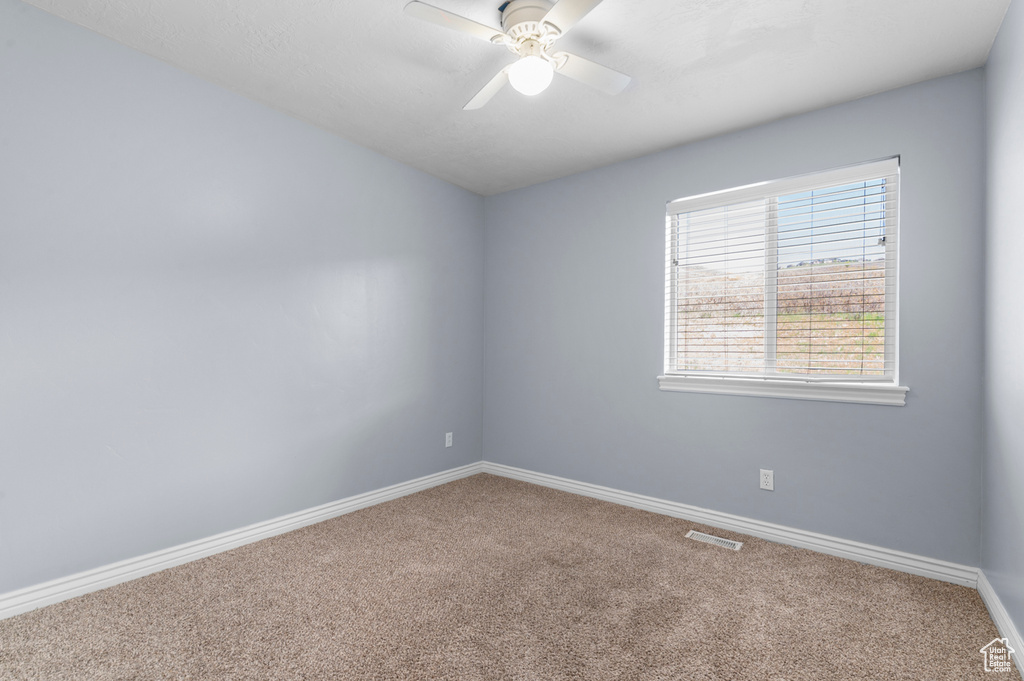 Carpeted spare room featuring baseboards and ceiling fan