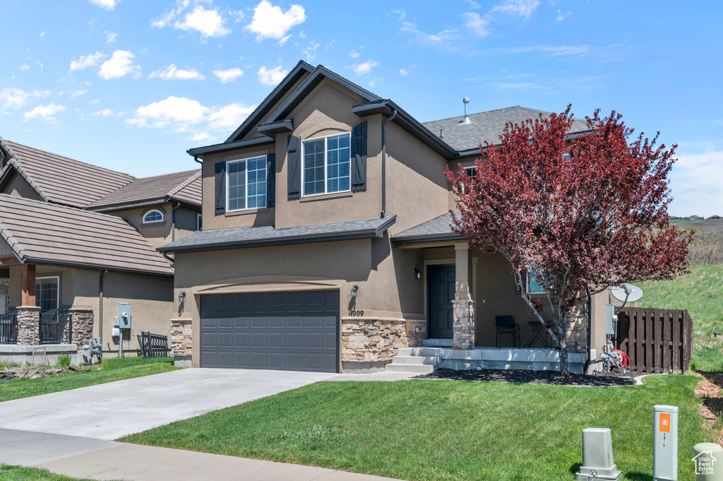 Traditional-style home with stucco siding, a garage, driveway, and stone siding