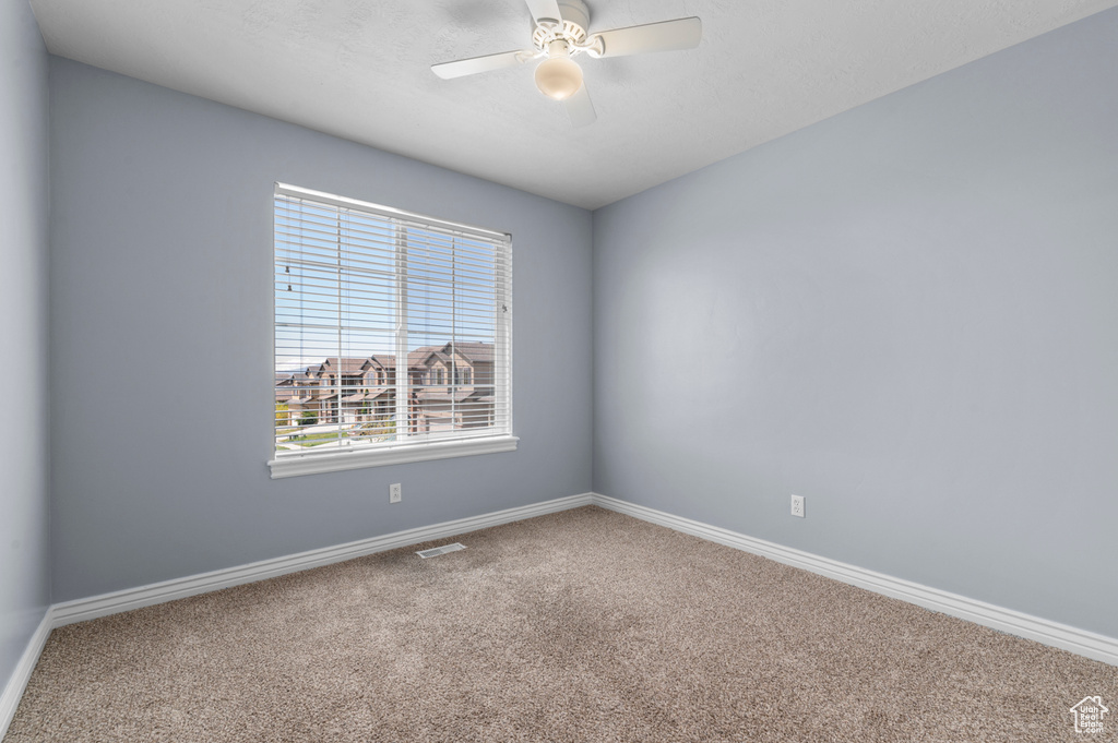 Carpeted spare room featuring baseboards and a ceiling fan