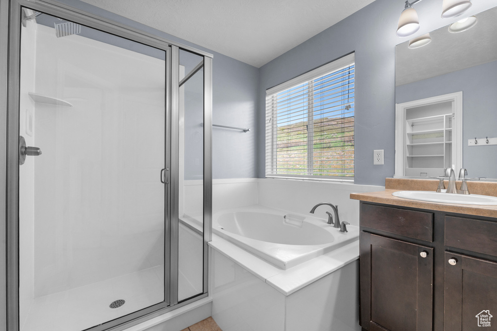 Full bathroom featuring a shower stall, a garden tub, and vanity