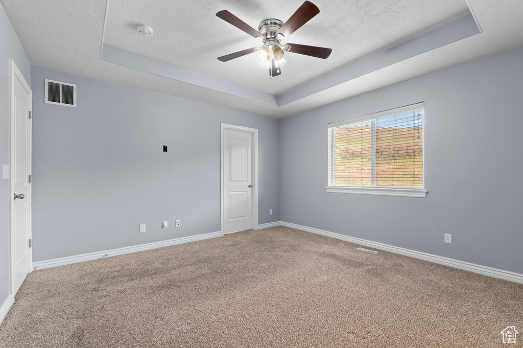 Carpeted spare room with a raised ceiling, a textured ceiling, ceiling fan, baseboards, and a smoke detector