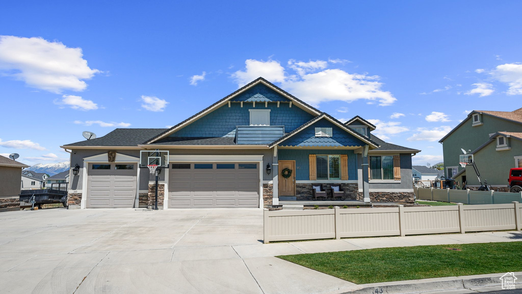 Craftsman house featuring fence, stone siding, an attached garage, and concrete driveway
