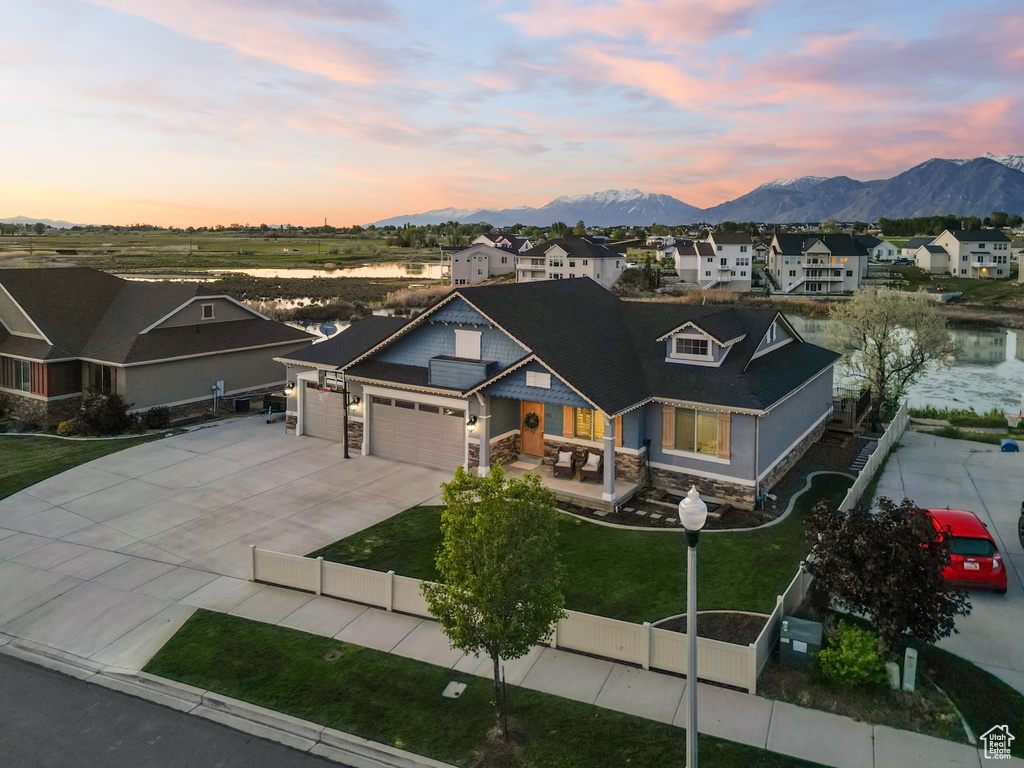 Craftsman house featuring stone siding, a mountain view, a garage, driveway, and a residential view