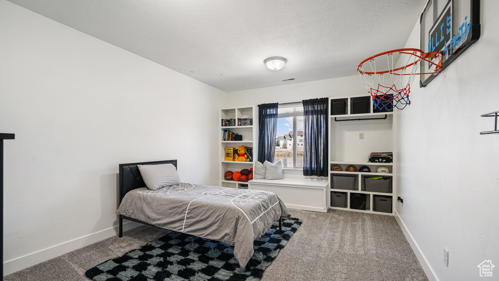 Bedroom featuring carpet floors, baseboards, and a textured ceiling