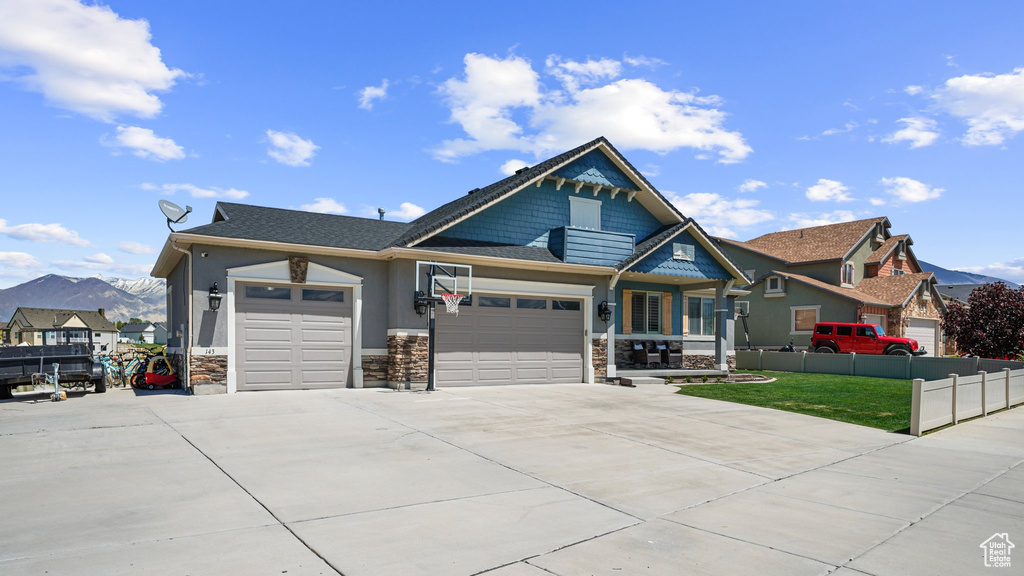 View of front facade featuring stone siding, a garage, driveway, and stucco siding