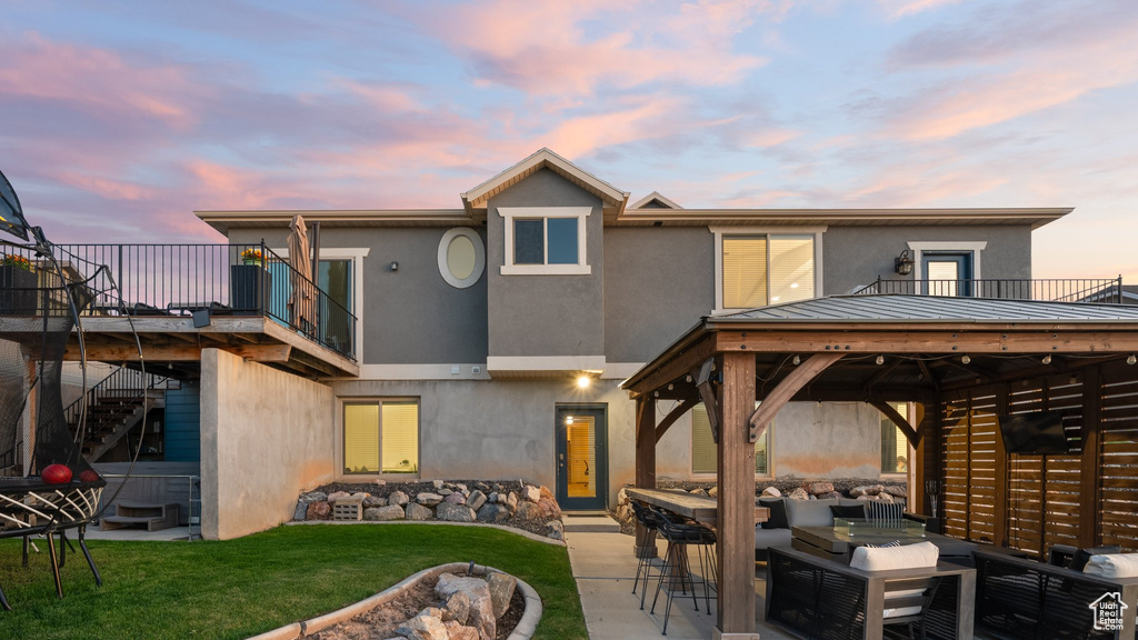 Back of property with stucco siding, a gazebo, a yard, an outdoor living space, and stairs