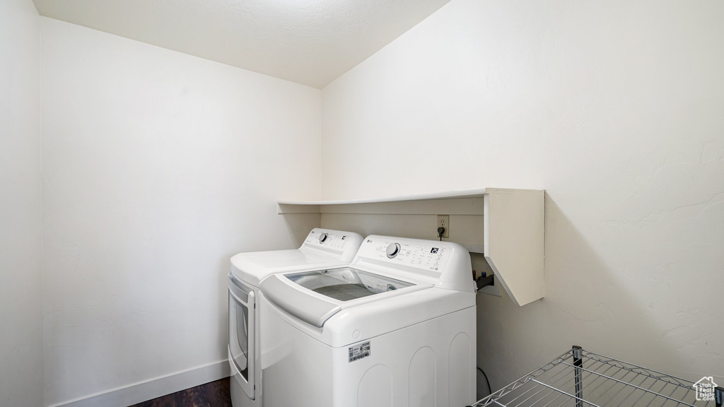 Washroom with washer and clothes dryer, dark wood-style flooring, and baseboards