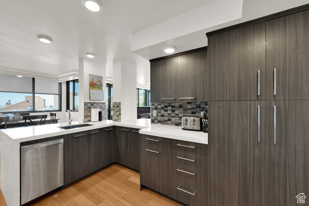 Kitchen featuring decorative backsplash, a sink, modern cabinets, and light countertops