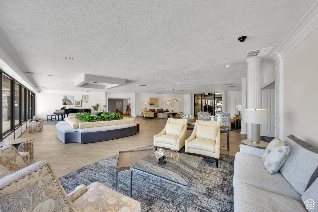 Living room with healthy amount of natural light, a textured ceiling, a chandelier, and wood finished floors