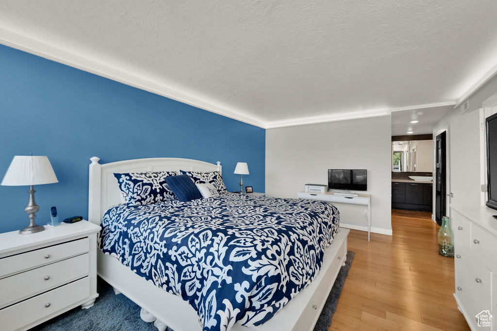 Bedroom with wood finished floors, a textured ceiling, and baseboards