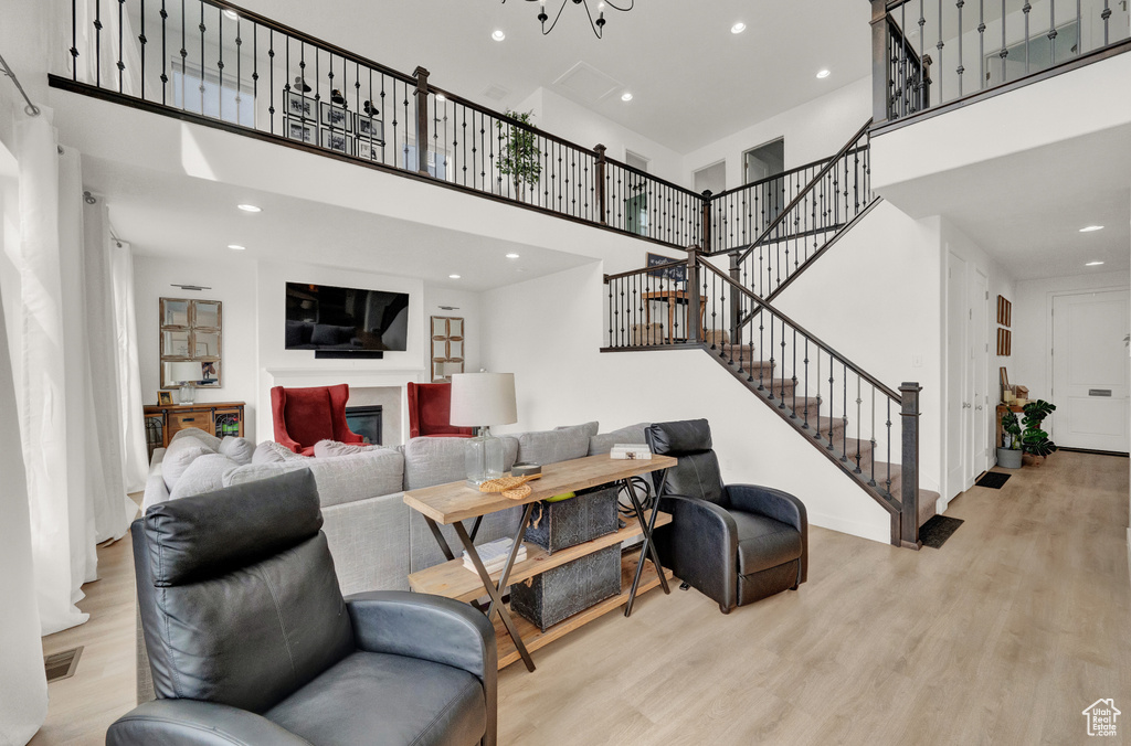 Living area with a towering ceiling, wood finished floors, stairway, and recessed lighting