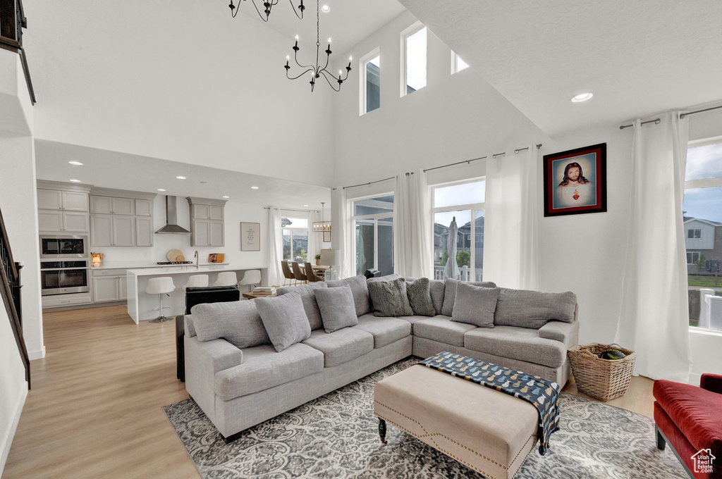 Living area featuring a chandelier, light wood finished floors, recessed lighting, and a high ceiling