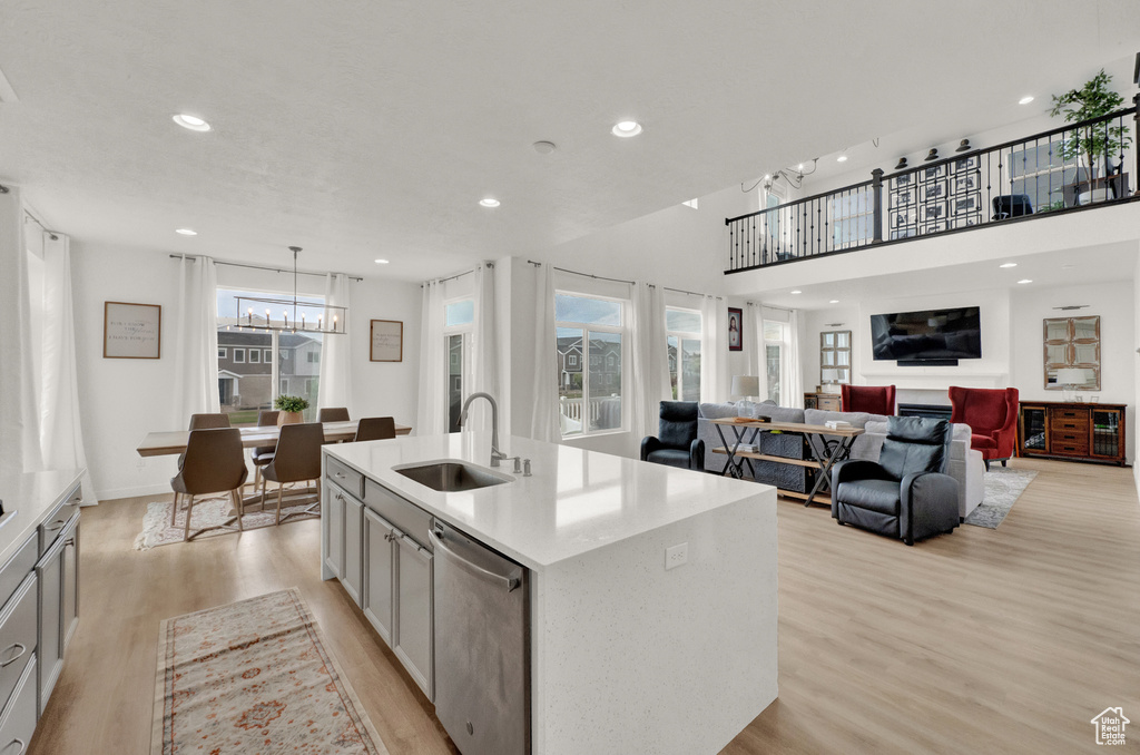 Kitchen featuring a sink, light wood-type flooring, a chandelier, light countertops, and a center island with sink