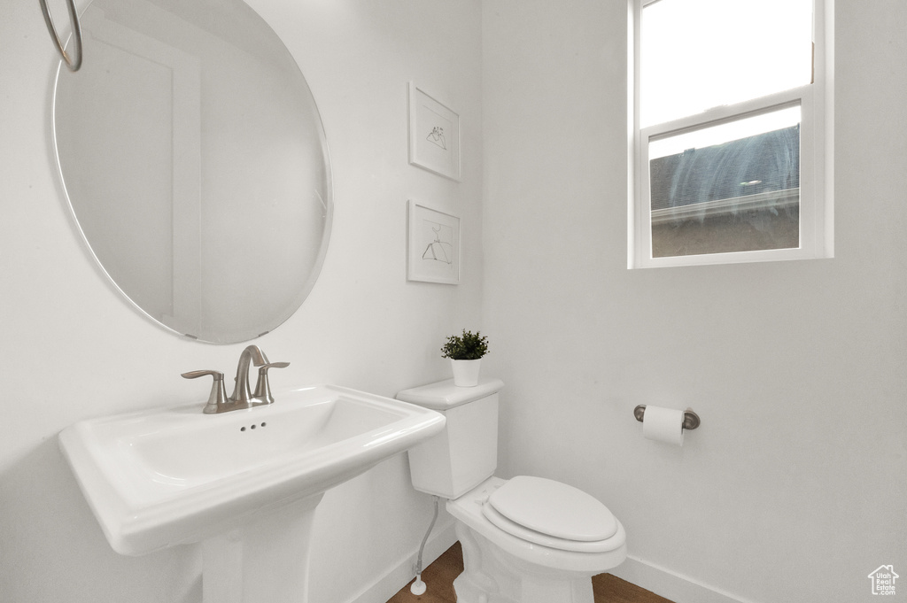Half bath with baseboards, toilet, and a sink