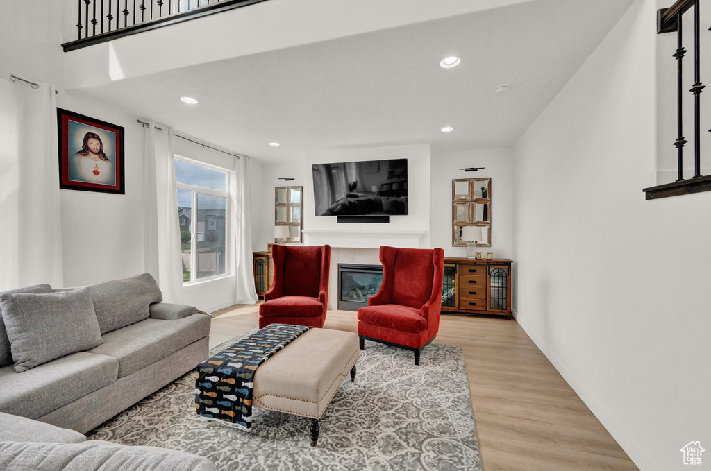Living room featuring wood finished floors, a glass covered fireplace, and recessed lighting