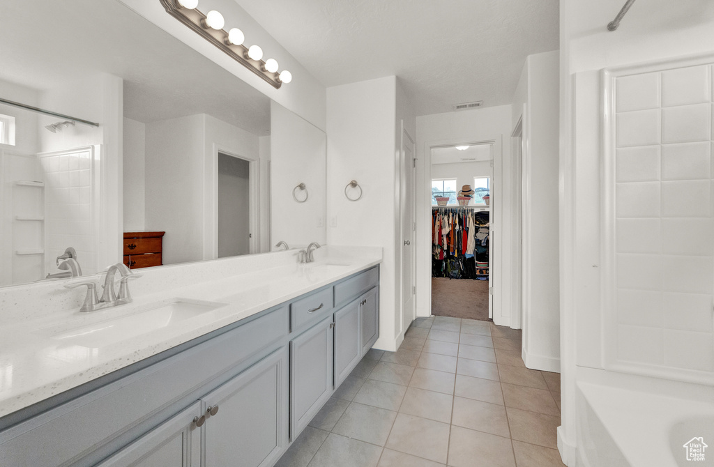 Full bath featuring tile patterned flooring, double vanity, and a walk in closet