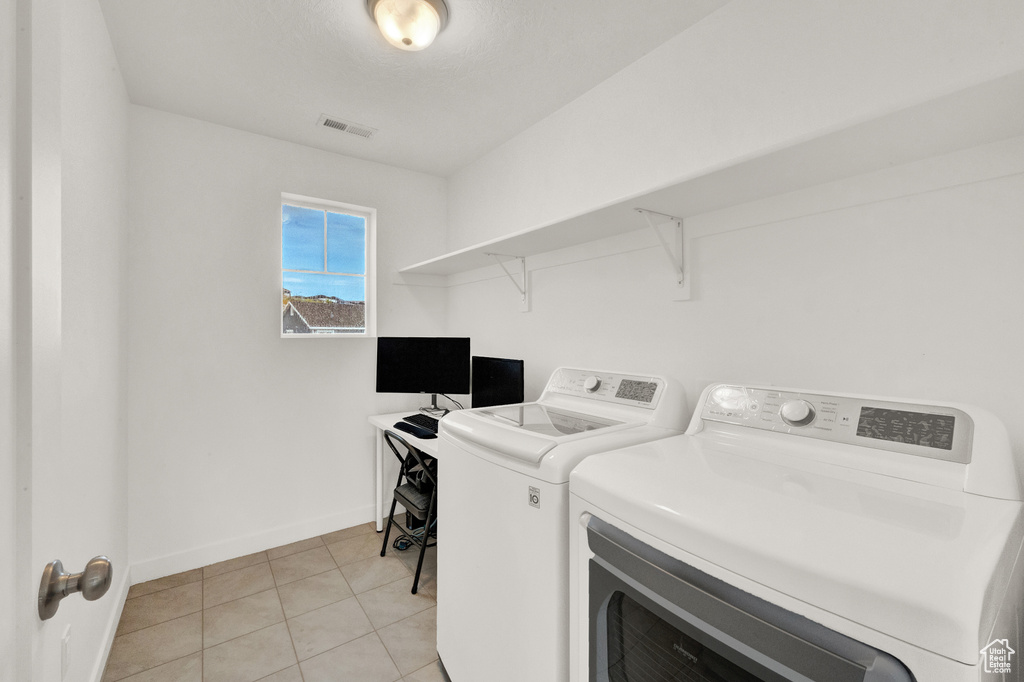 Washroom with washing machine and dryer, baseboards, and light tile patterned flooring