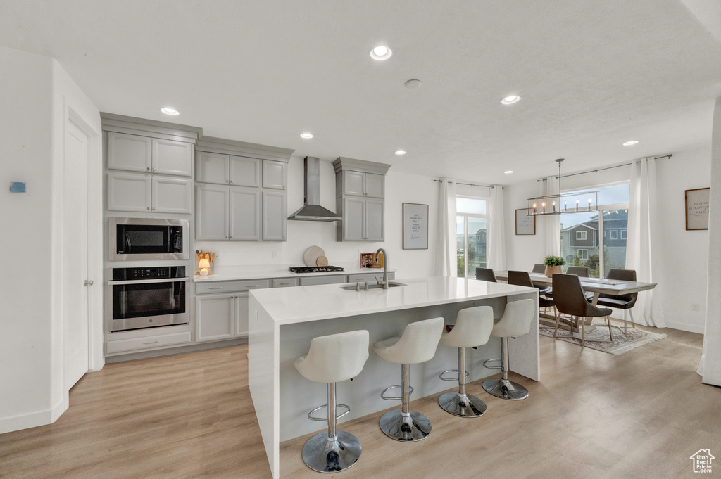 Kitchen with oven, wall chimney range hood, a sink, built in microwave, and gray cabinets