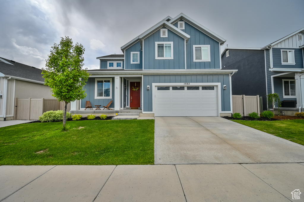 Traditional-style house with board and batten siding, covered porch, driveway, and an attached garage