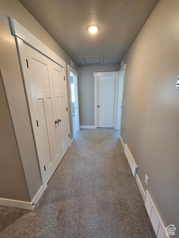 Corridor featuring carpet floors, a textured ceiling, and baseboards