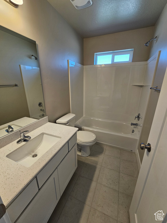 Full bath featuring shower / tub combination, toilet, vanity, a textured ceiling, and tile patterned floors