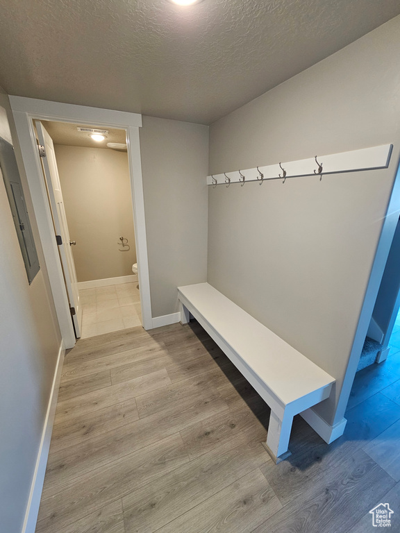 Mudroom featuring a textured ceiling, wood finished floors, baseboards, and electric panel