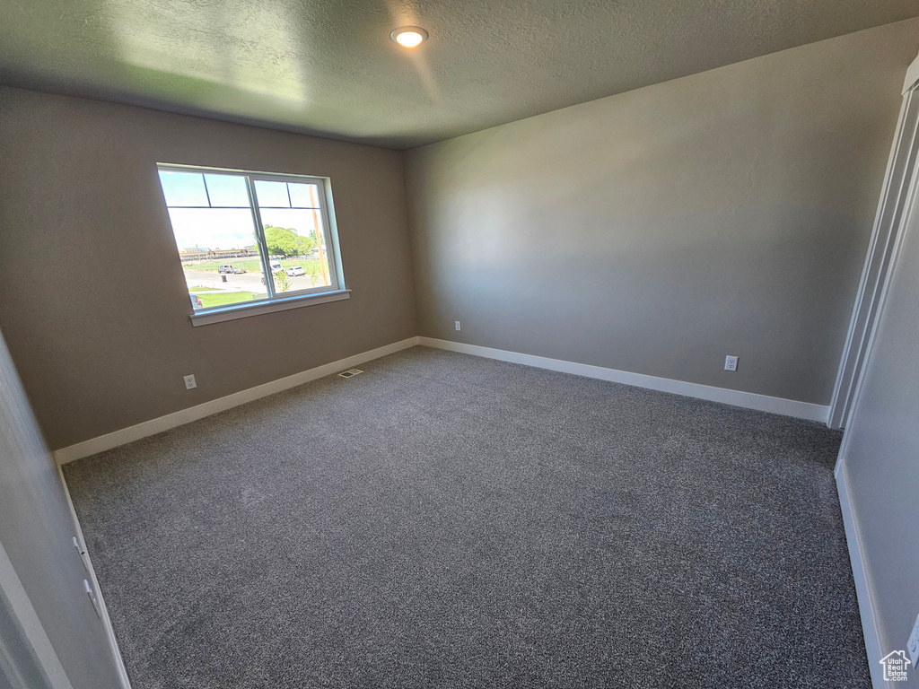 Unfurnished room with a textured ceiling, carpet floors, and baseboards