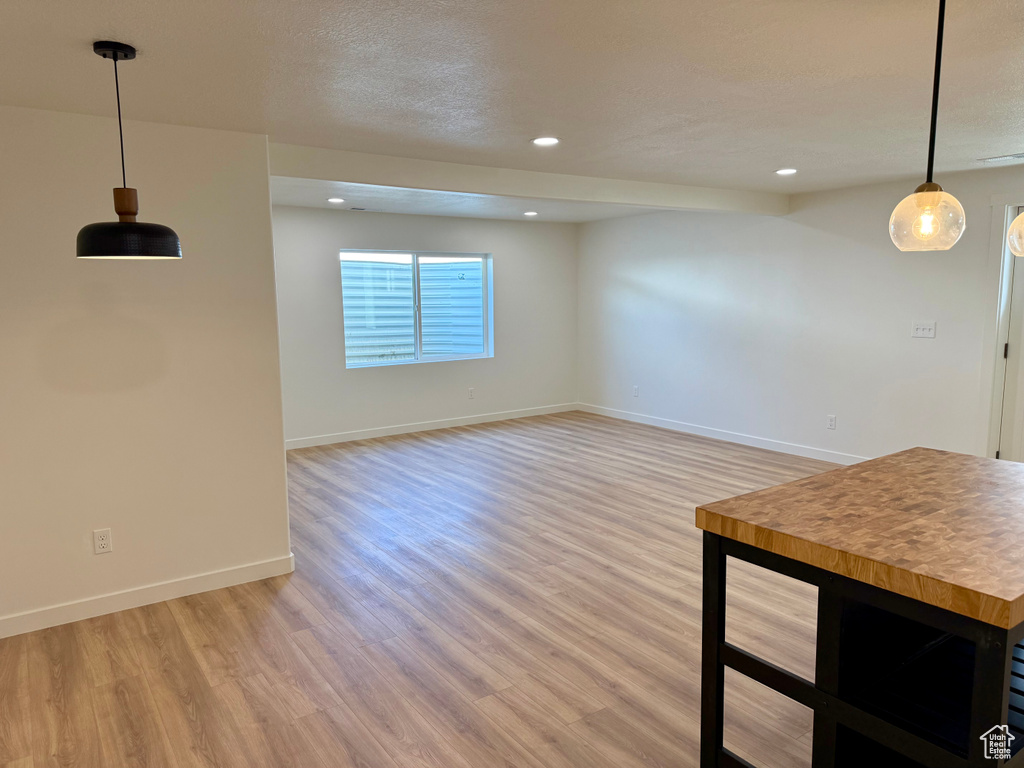 Unfurnished living room featuring light wood-style floors, baseboards, recessed lighting, and a textured ceiling