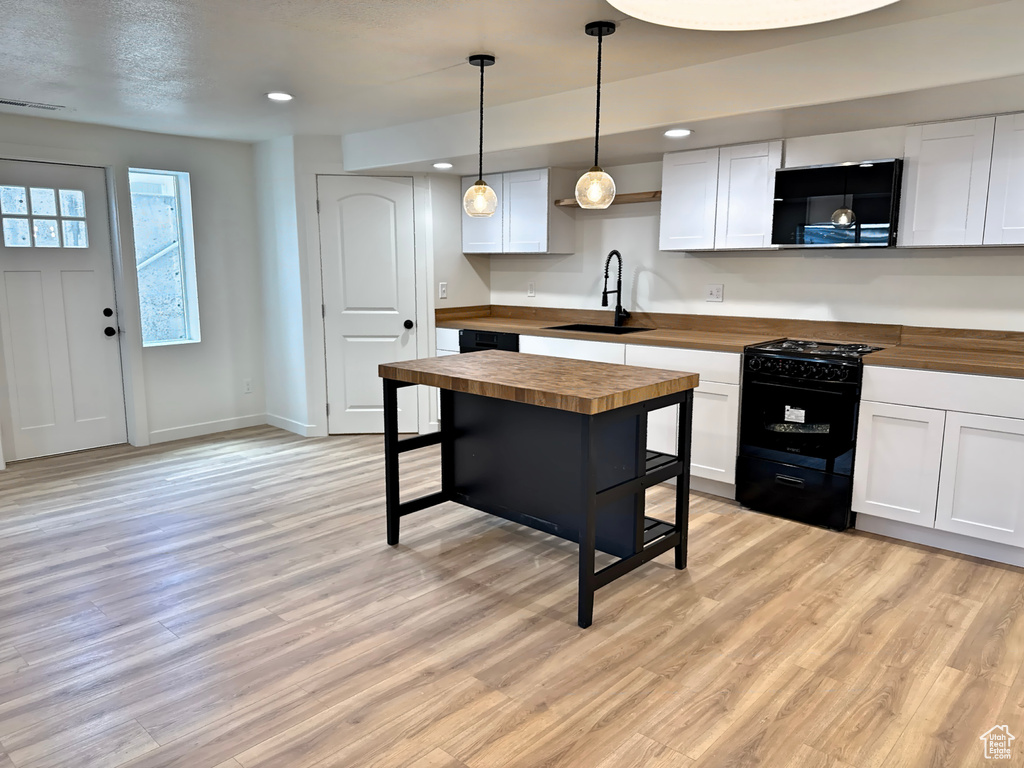 Kitchen featuring wood counters, a sink, black appliances, light wood-style floors, and open shelves