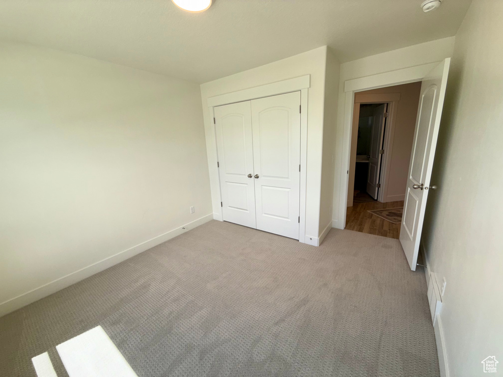 Unfurnished bedroom with carpet, a closet, and baseboards
