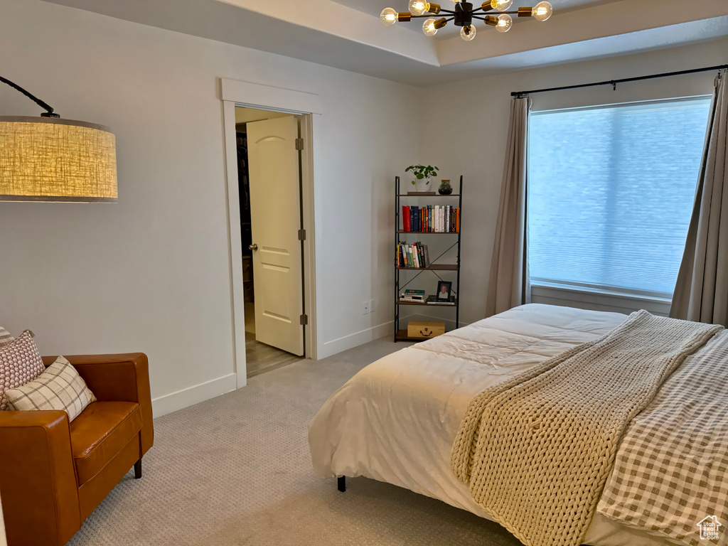 Bedroom featuring a chandelier, light carpet, and baseboards