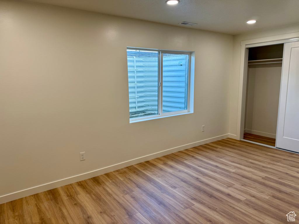 Unfurnished bedroom with wood finished floors, recessed lighting, baseboards, and a closet