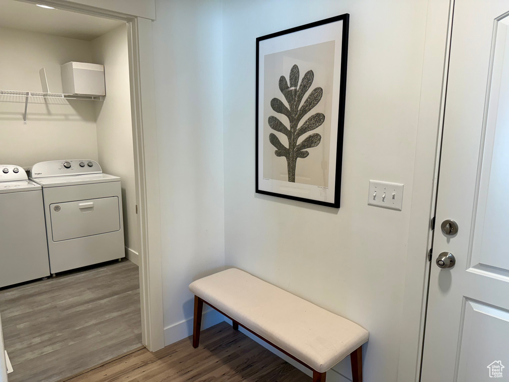 Laundry room with washing machine and dryer, light wood-type flooring, and baseboards