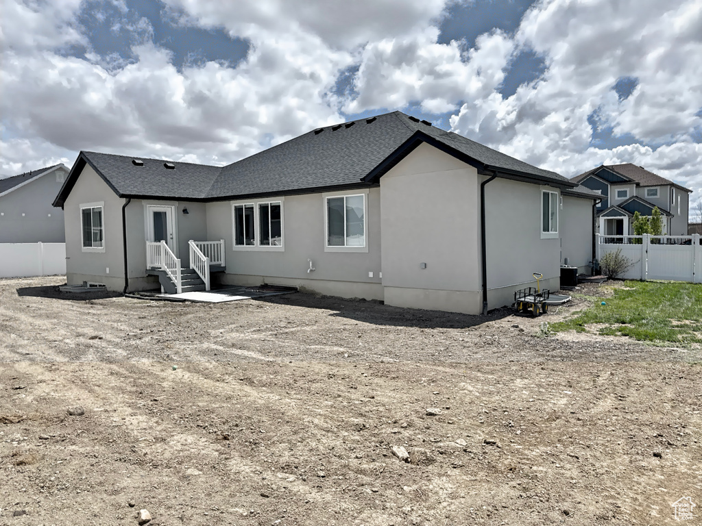 Back of property with fence, stucco siding, and a shingled roof