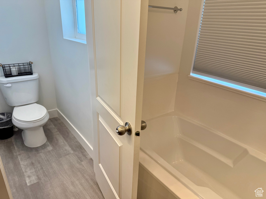 Full bath featuring toilet, a bathtub, baseboards, and wood finished floors