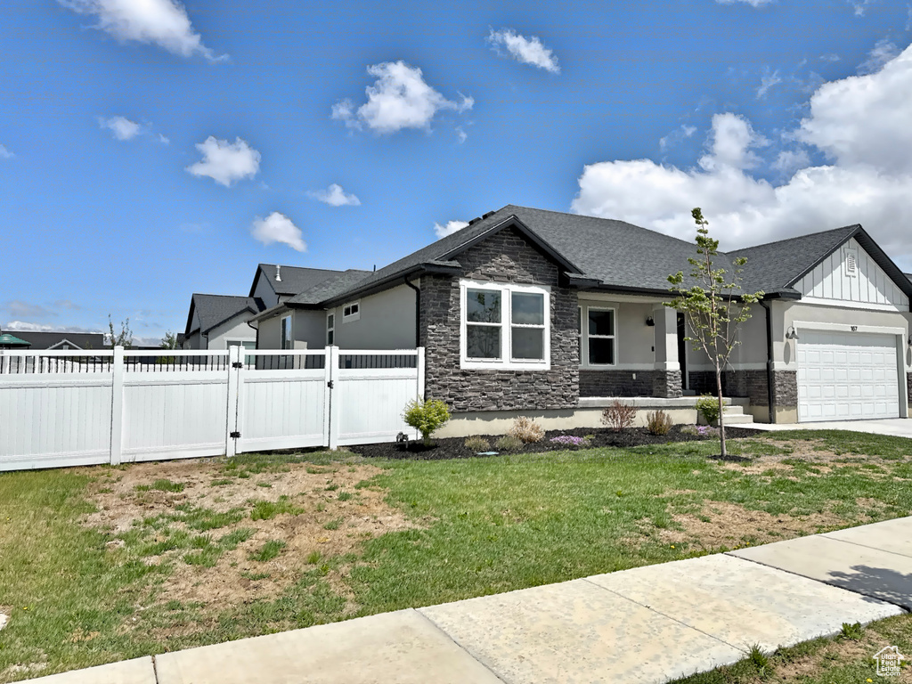 View of front of home featuring stone siding, a gate, a garage, board and batten siding, and concrete driveway