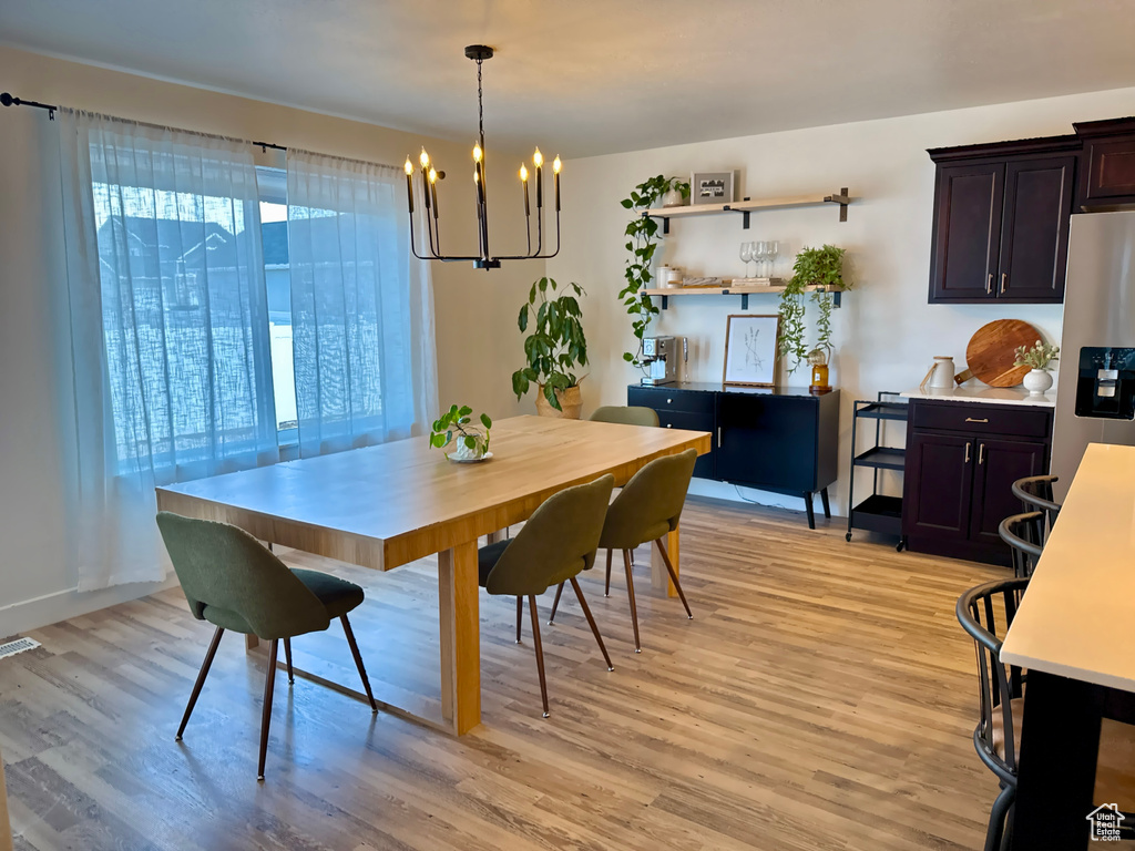 Dining room featuring a chandelier, light wood-style flooring, and baseboards