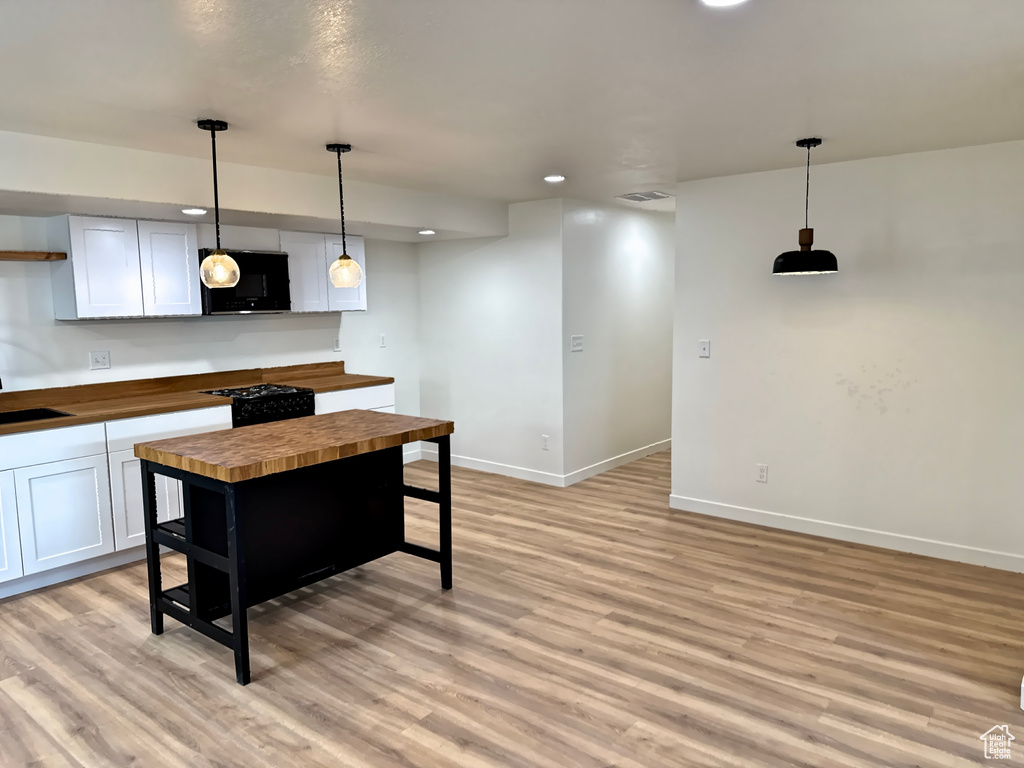 Kitchen with wood counters, black microwave, light wood-style floors, baseboards, and recessed lighting