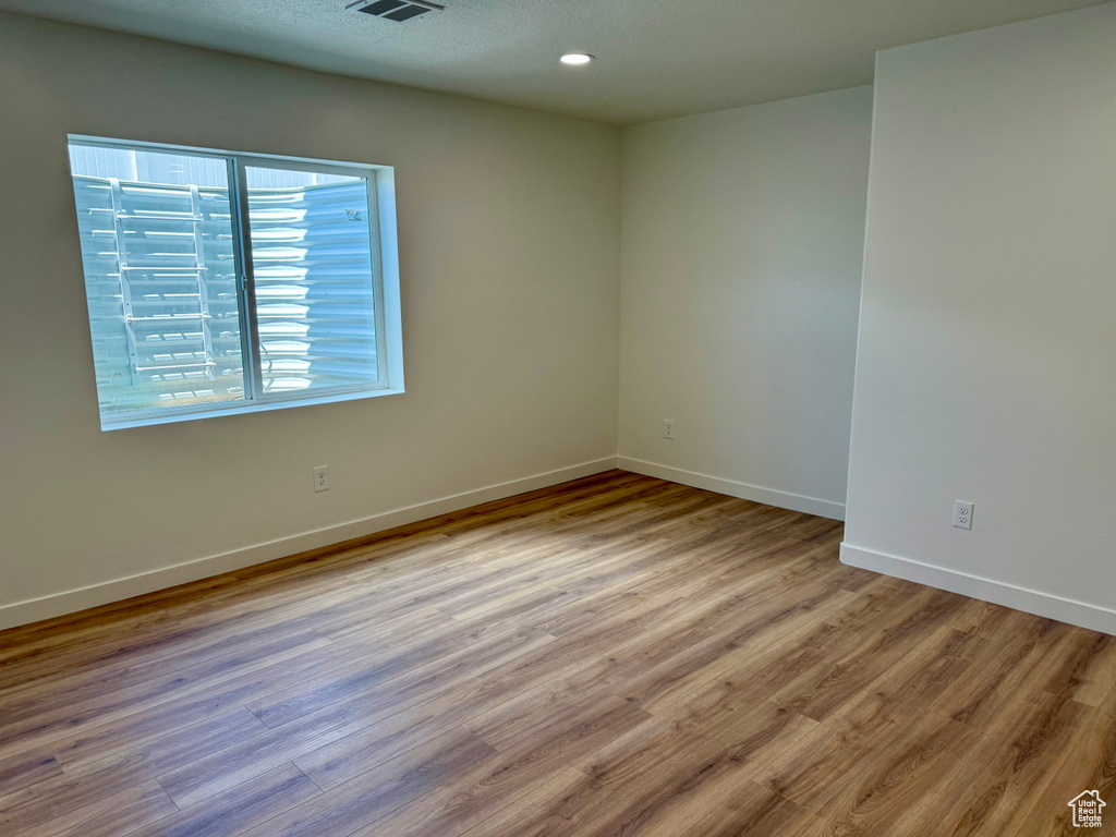 Spare room with wood finished floors, baseboards, and recessed lighting