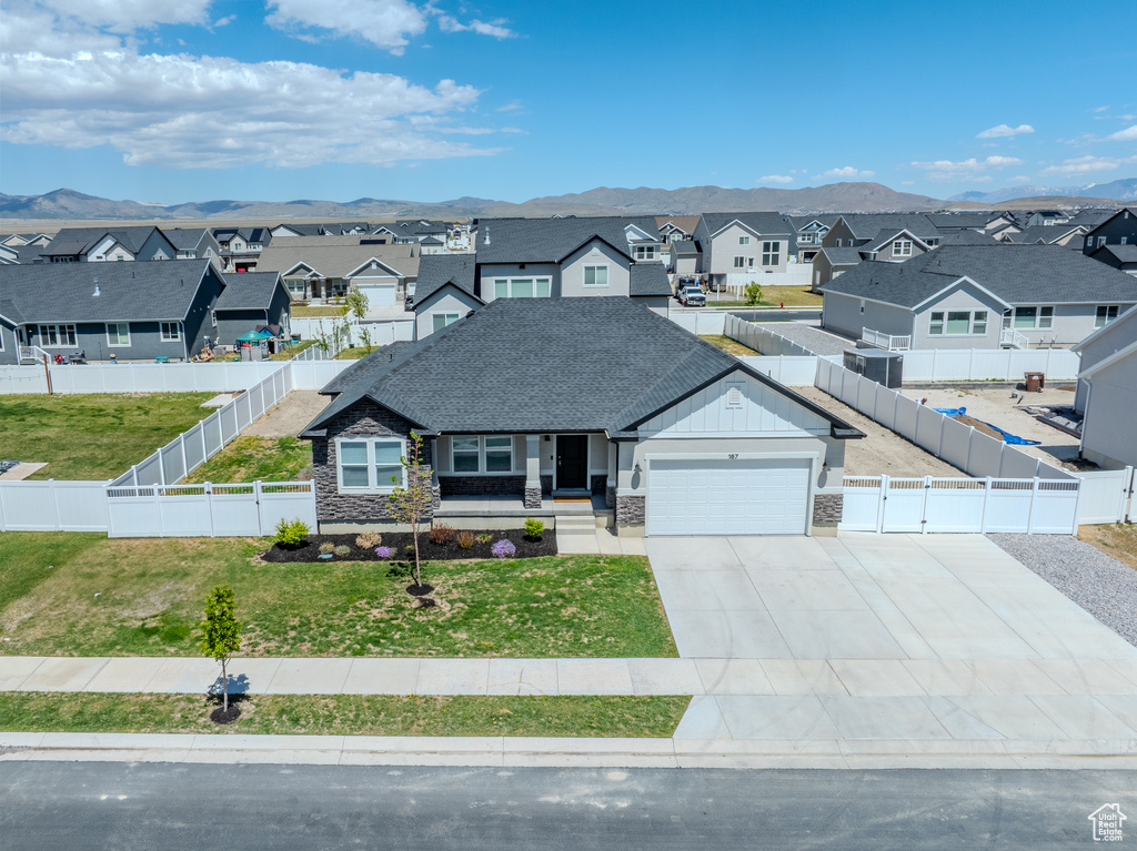 View of front of home featuring a residential view, a garage, stone siding, and concrete driveway