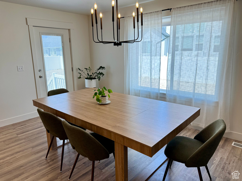 Dining space featuring a chandelier, baseboards, healthy amount of natural light, and light wood-style flooring