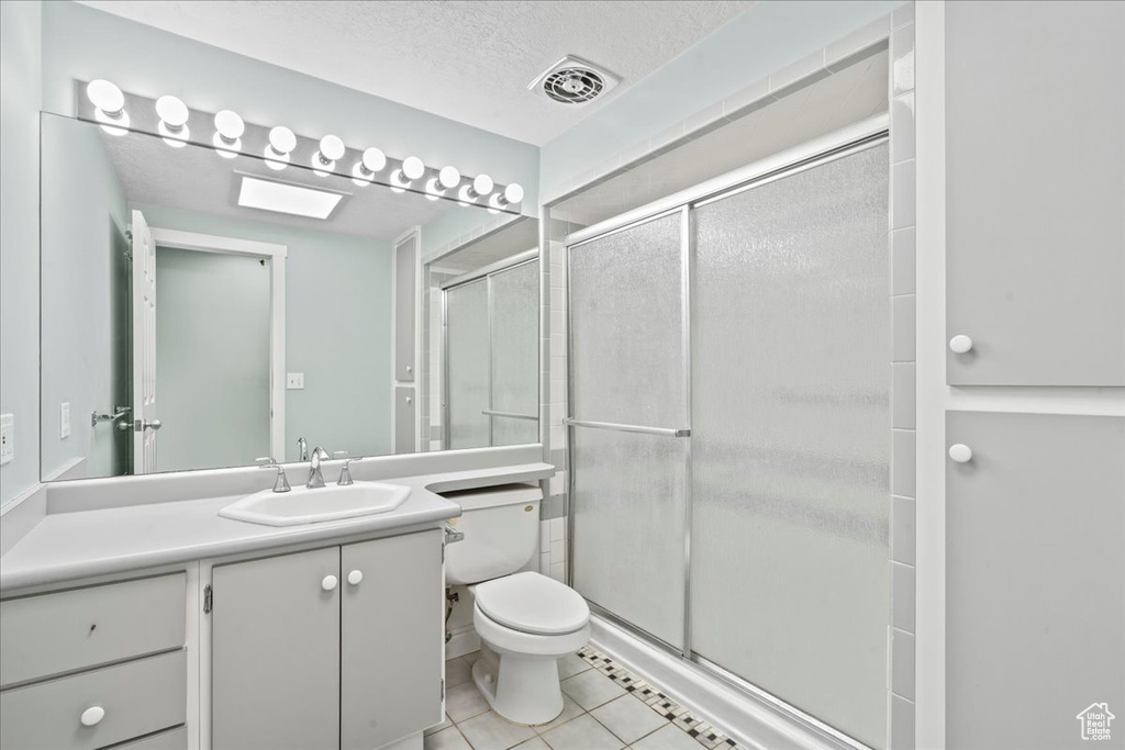 Full bathroom with toilet, a stall shower, tile patterned flooring, vanity, and a textured ceiling
