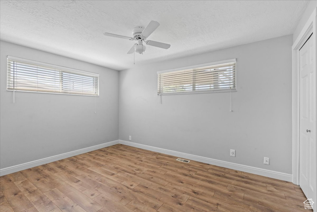 Unfurnished bedroom with multiple windows, a closet, light wood-style flooring, and a textured ceiling