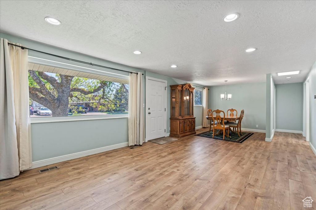 Dining area featuring a textured ceiling, baseboards, light wood finished floors, recessed lighting, and a chandelier