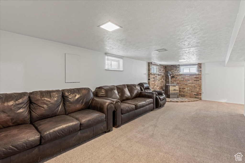 Living room with a wood stove, carpet floors, a textured ceiling, and plenty of natural light