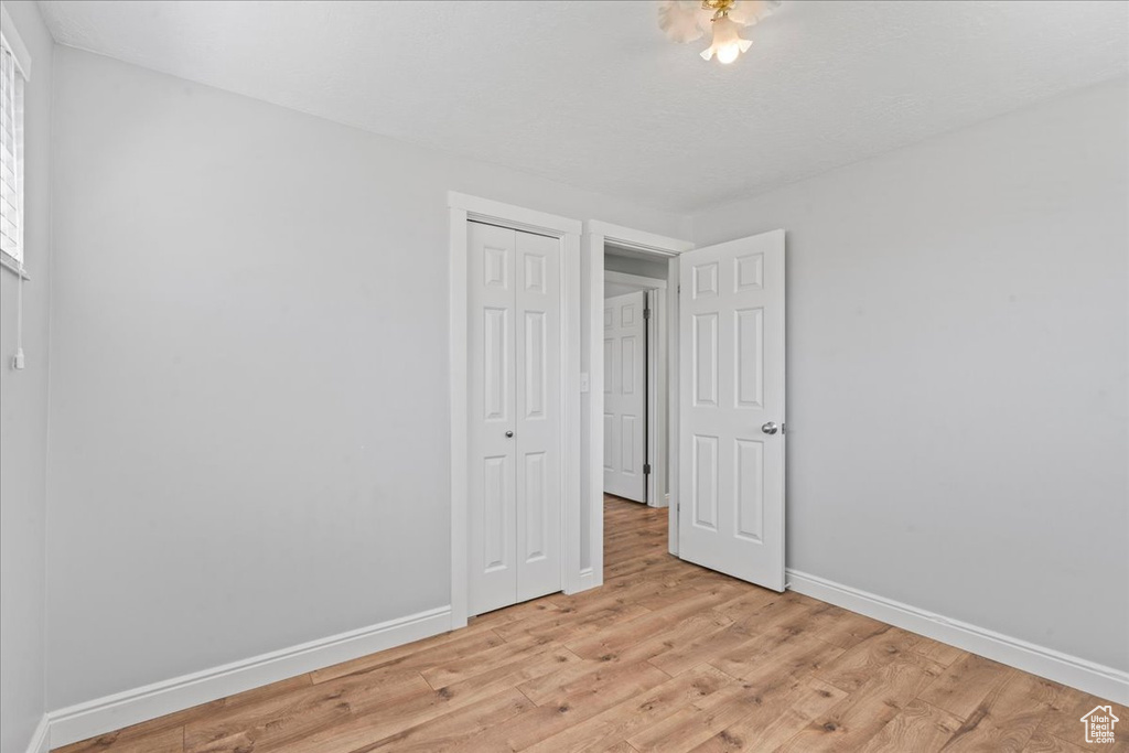 Unfurnished bedroom featuring baseboards, a closet, and light wood finished floors