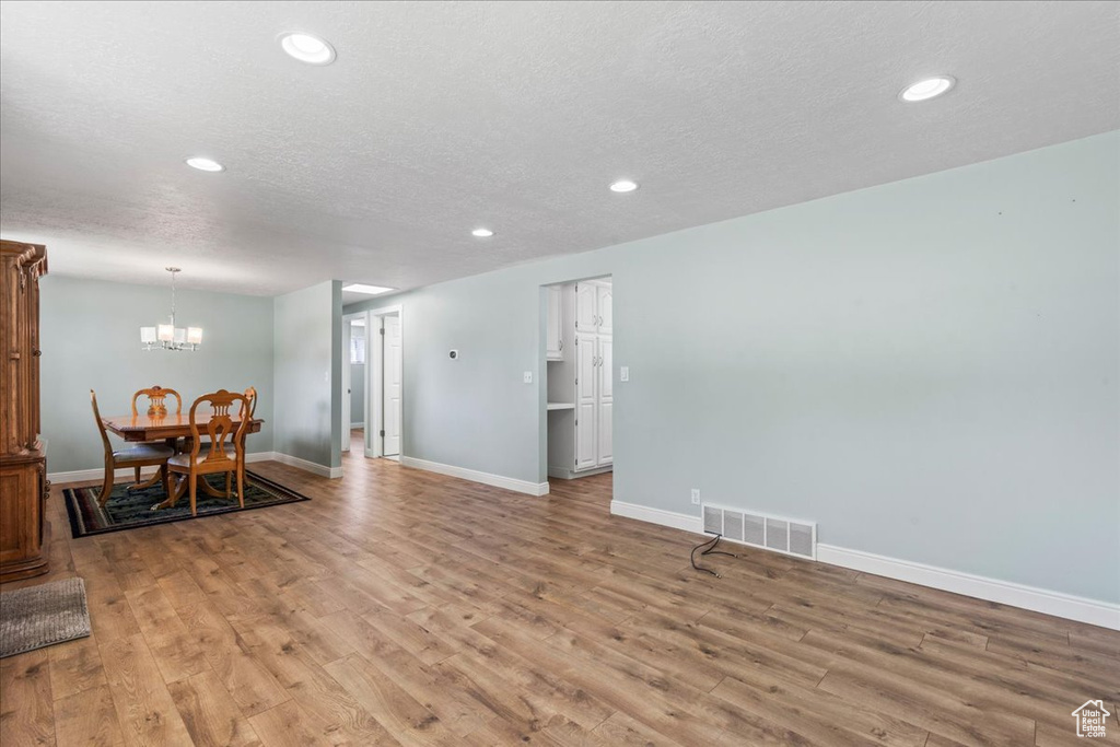 Living area with a chandelier, light wood-style flooring, recessed lighting, baseboards, and a textured ceiling