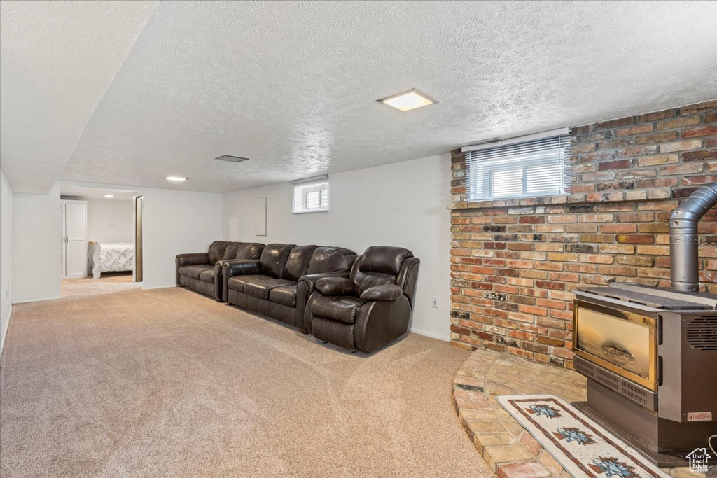 Living room with a wood stove, carpet floors, a textured ceiling, and baseboards
