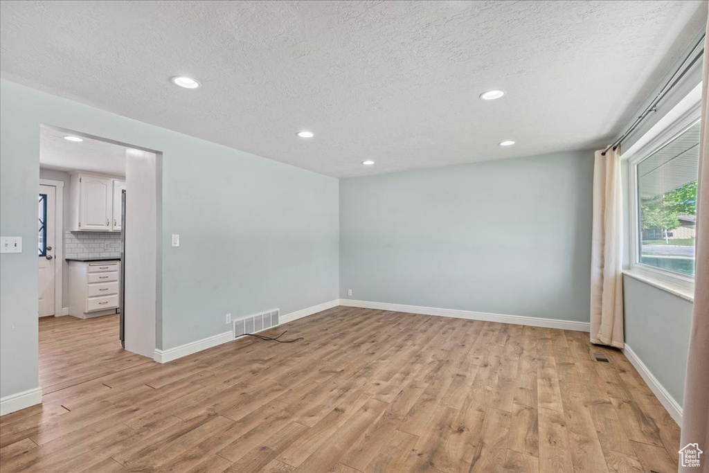 Unfurnished room featuring light wood finished floors, recessed lighting, a textured ceiling, and baseboards