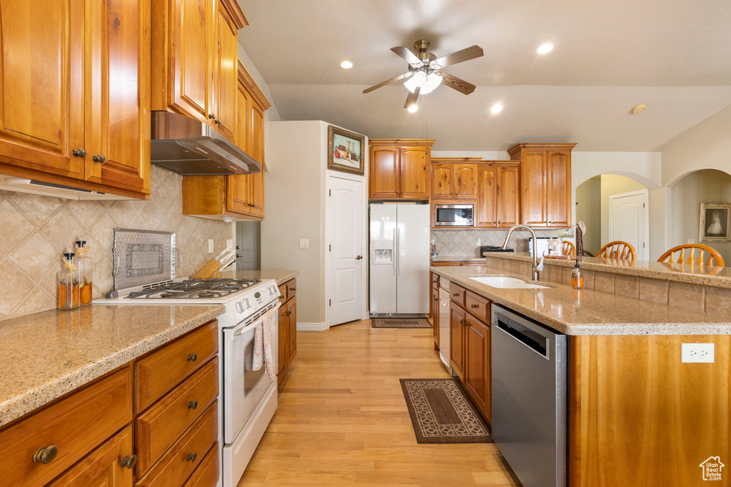 Kitchen featuring ceiling fan, a sink, under cabinet range hood, stainless steel appliances, and light wood-style flooring
